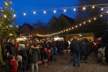 Waldhilsbacher Weihnachtsmarkt an Abend mit Menschen im Vordergrund und Hütten im Hintergrund