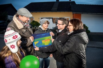 Familie vor ihrem Haus mit Thermografie-Bild